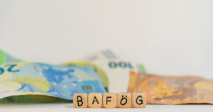 Geldscheine und Holzbuchsstaben stehen für BAföG. Gibt es durch die Haushaltskürzung 2024 weniger BAföG für Studierende?